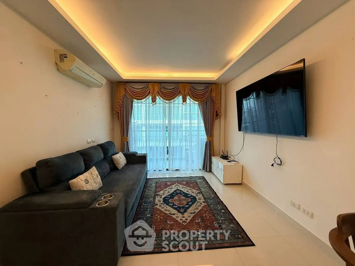 Spacious living room with modern sofa, large TV, and elegant curtains.