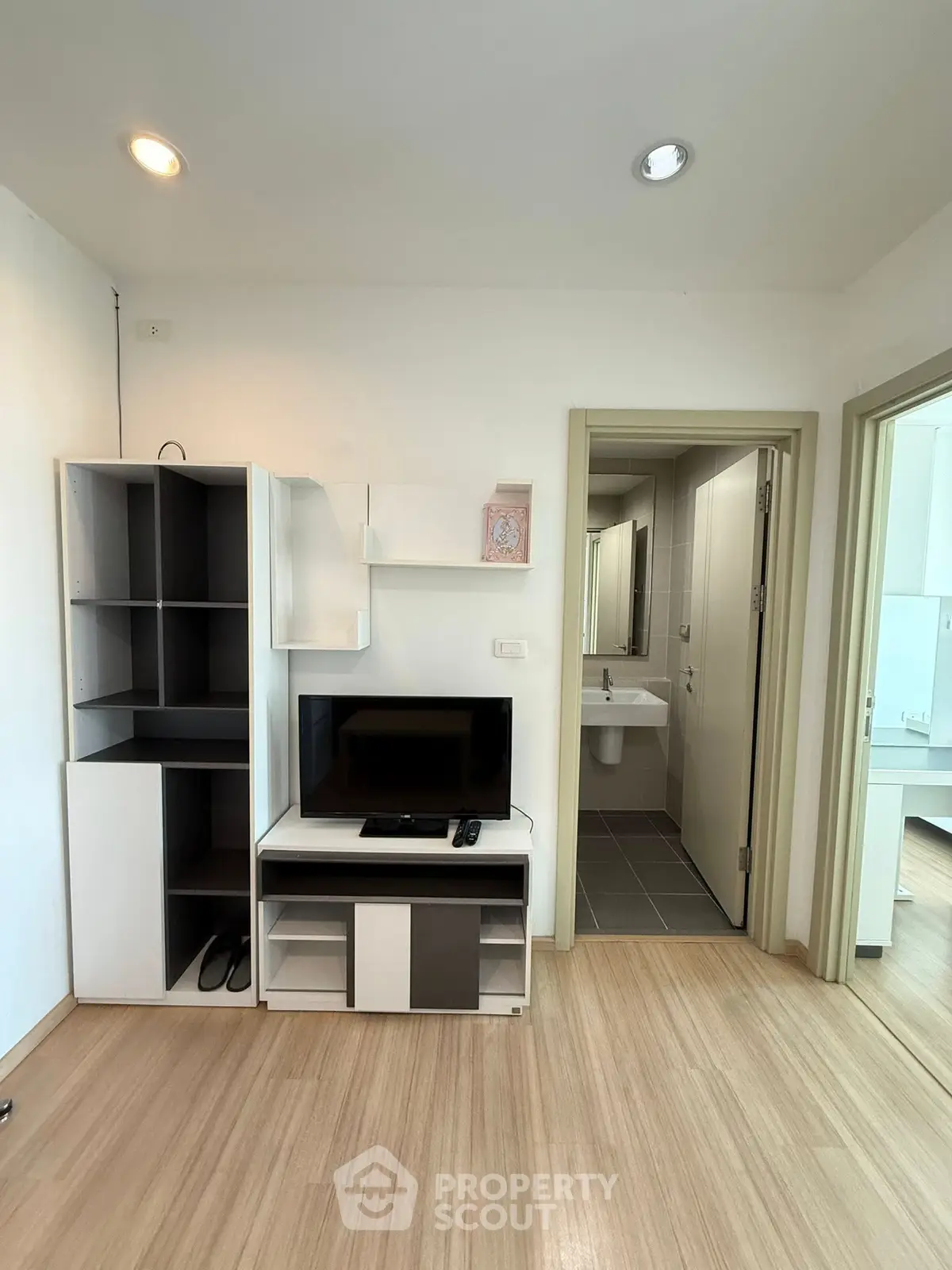 Modern apartment interior with TV unit and bathroom entrance, showcasing sleek design and functionality.
