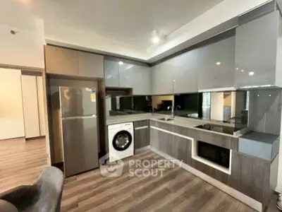 Modern kitchen with sleek cabinetry, stainless steel appliances, and washing machine in open layout.