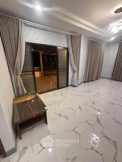 Spacious living room with elegant curtains and marble flooring, leading to a balcony.