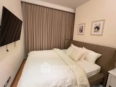 Cozy bedroom with modern decor and wall-mounted TV, perfect for relaxation.