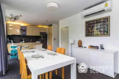 Modern dining area with sleek kitchen and stylish decor in open layout apartment.