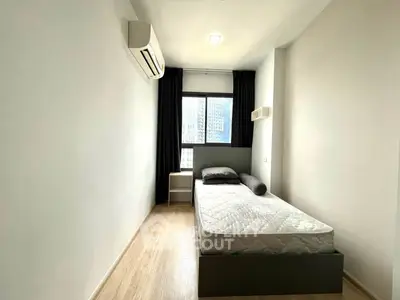 Modern minimalist bedroom with single bed and air conditioning in a high-rise apartment.