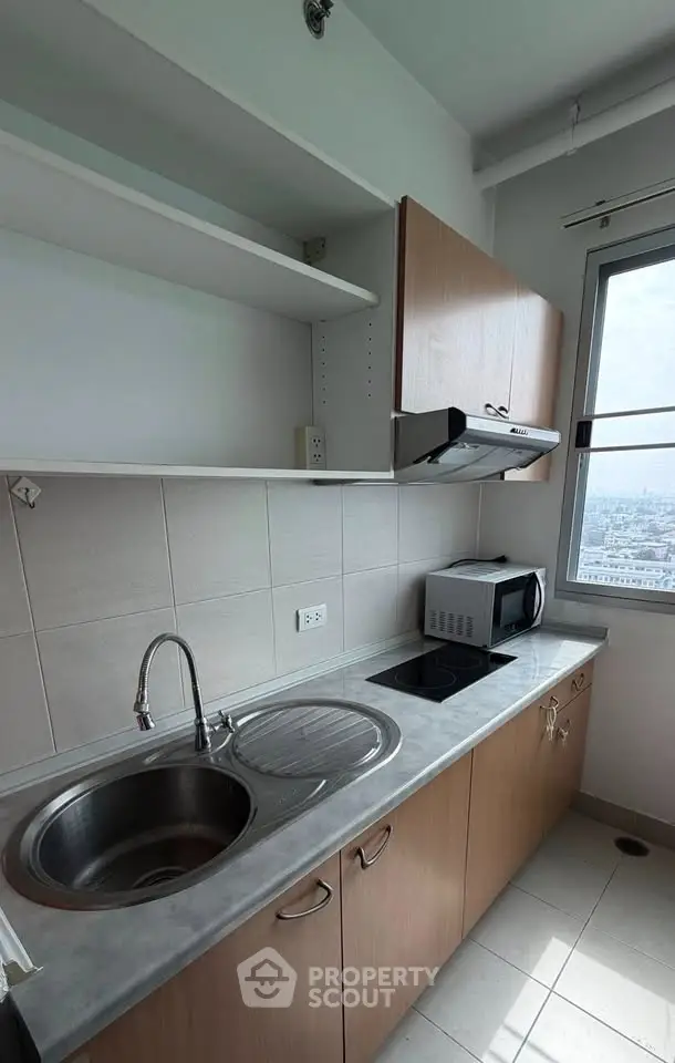 Modern kitchen with sleek cabinetry and city view, featuring a microwave and electric stove.