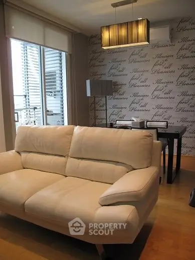 Modern living room with stylish sofa and dining area, featuring elegant wallpaper and natural light.