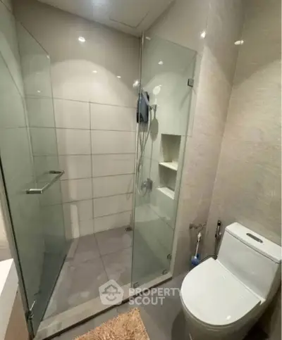 Modern bathroom with glass shower enclosure and sleek toilet design.