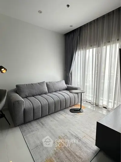 Modern living room with stylish gray sofa and floor-to-ceiling windows