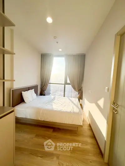 Bright and cozy bedroom with large window and city view, perfect for relaxation.