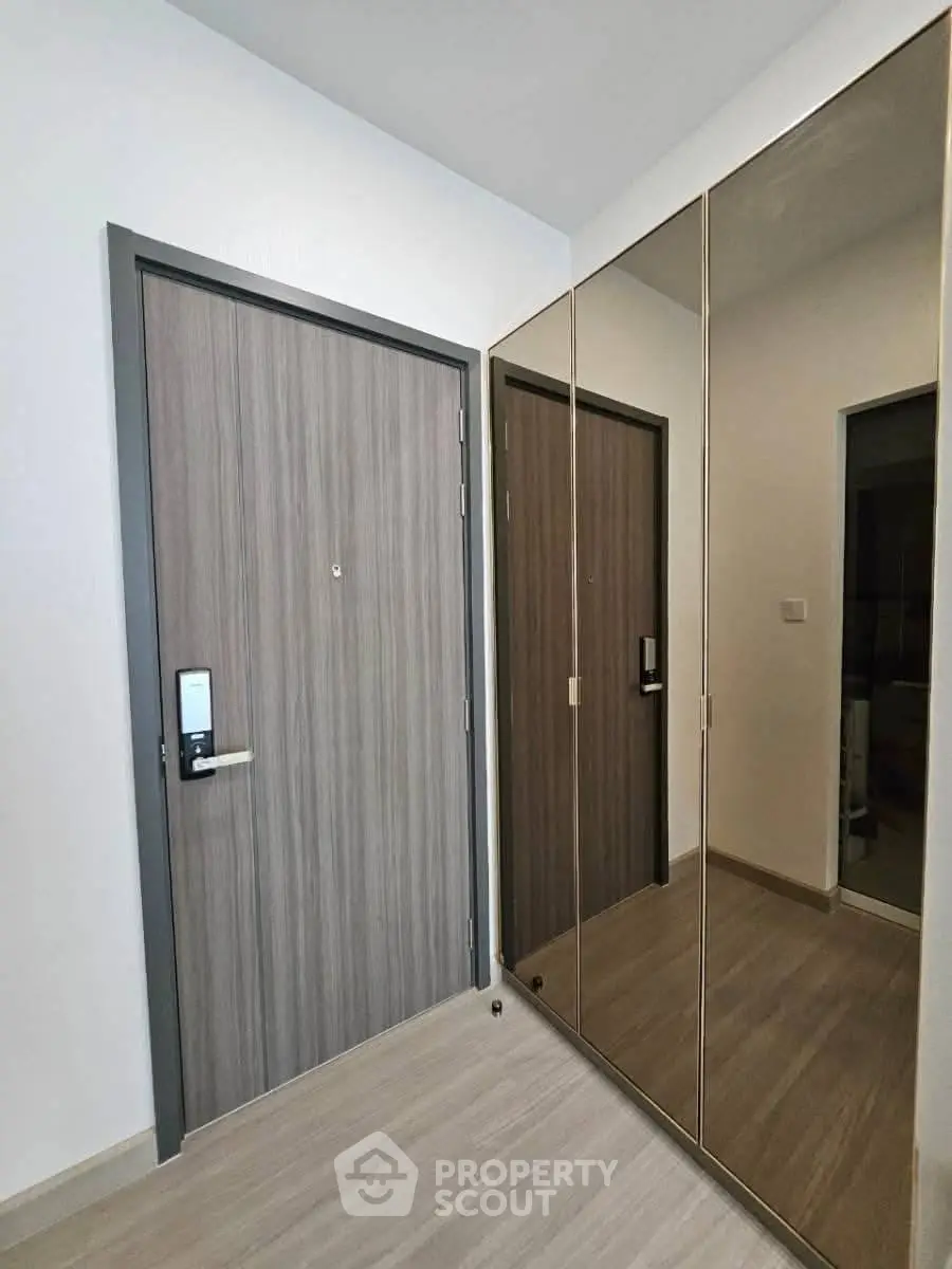 Modern apartment entrance with sleek mirrored closet and electronic door lock.