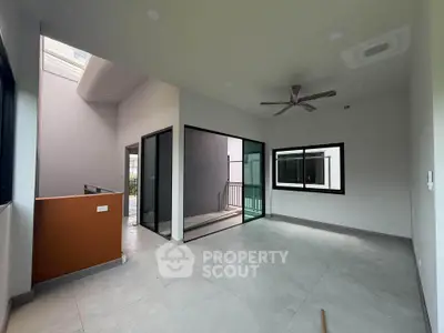 Spacious modern living room with large windows and ceiling fan
