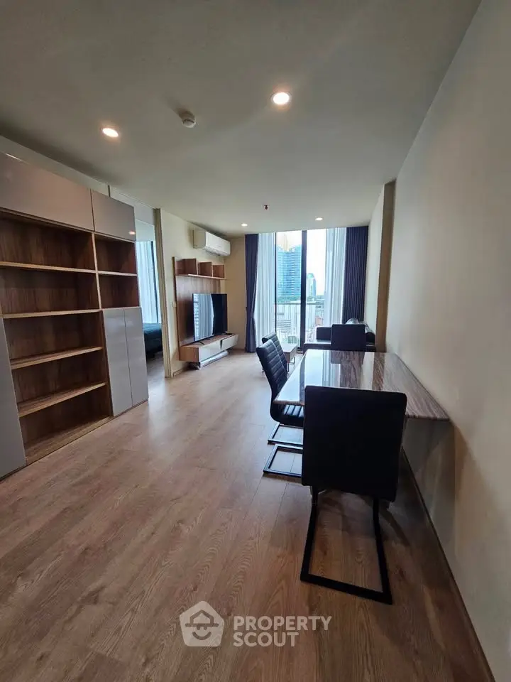 Spacious modern living room with city view, wooden flooring, and elegant furniture.