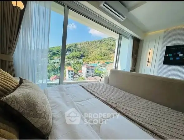 Luxurious bedroom with stunning panoramic view of lush green hills and cityscape.