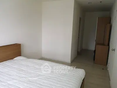 Spacious bedroom with minimalist design and wooden furniture, perfect for modern living.