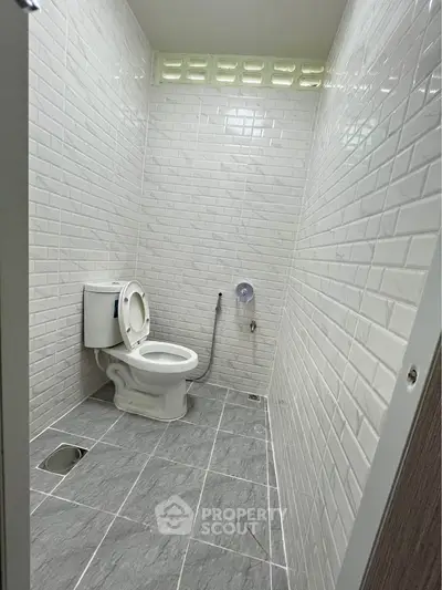 Modern minimalist bathroom with white subway tiles and sleek gray flooring.