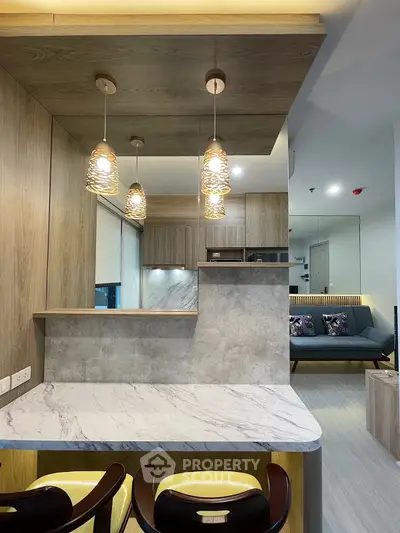 Modern kitchen with marble countertop and stylish pendant lights in open layout apartment.