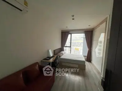 Cozy bedroom with city view, featuring a bed, desk, and air conditioning, perfect for urban living.