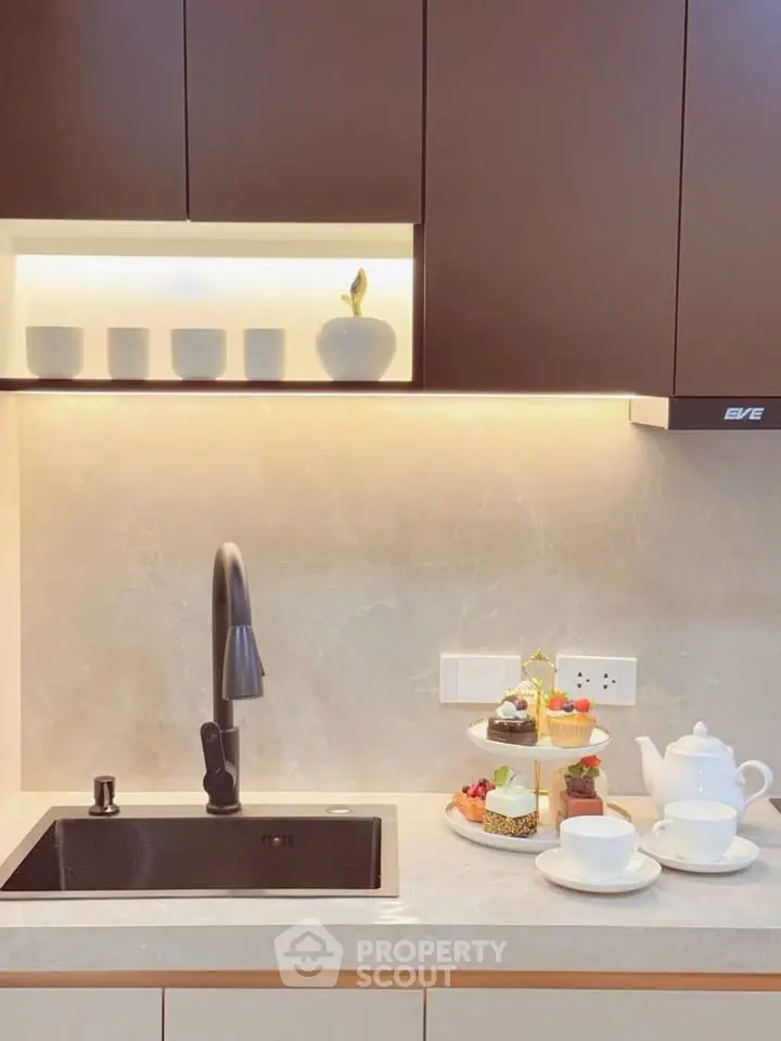 Modern kitchen with elegant cabinetry and stylish sink, featuring a delightful tea set and pastries.