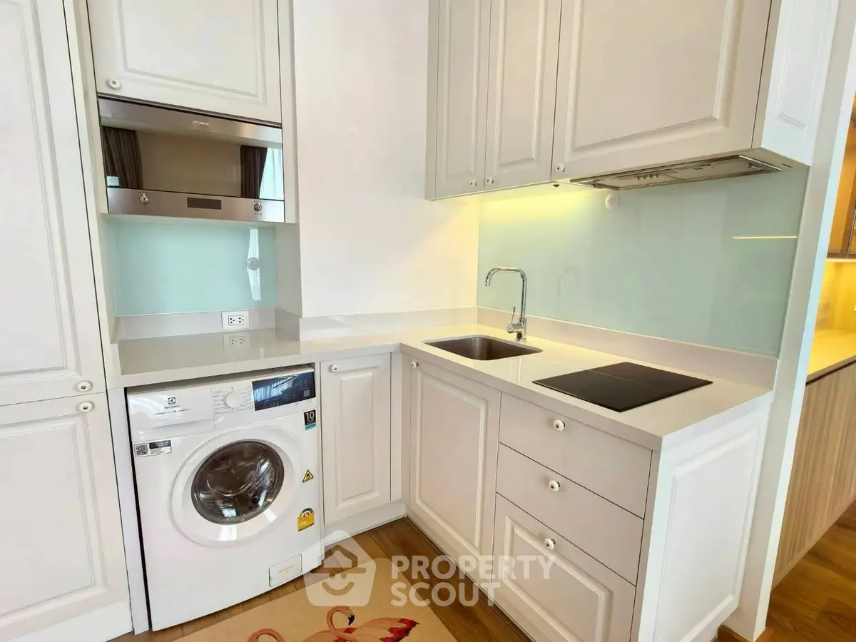 Modern kitchen with washing machine and sleek cabinetry in compact layout.