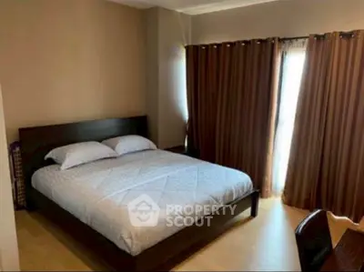 Spacious bedroom with large bed and natural light through curtains.