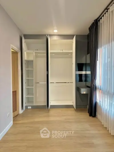 Spacious bedroom with open wardrobe and large window for natural light