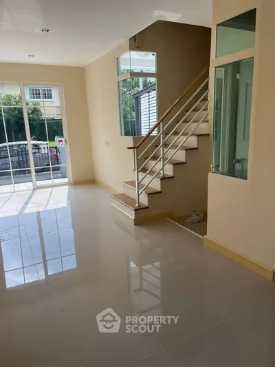 Bright and airy living room with staircase and large windows