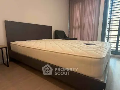 Spacious bedroom with modern bed and natural light through large window.