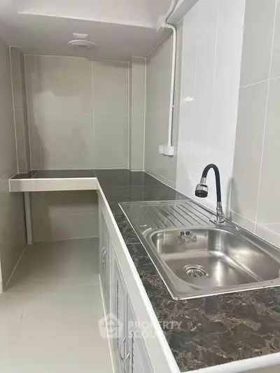 Modern kitchen with sleek countertops and stainless steel sink in a compact layout.
