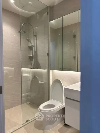 Modern bathroom with glass shower and sleek fixtures in luxury apartment.