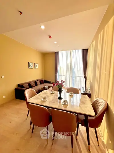 Elegant living room with modern dining set and large windows offering natural light.
