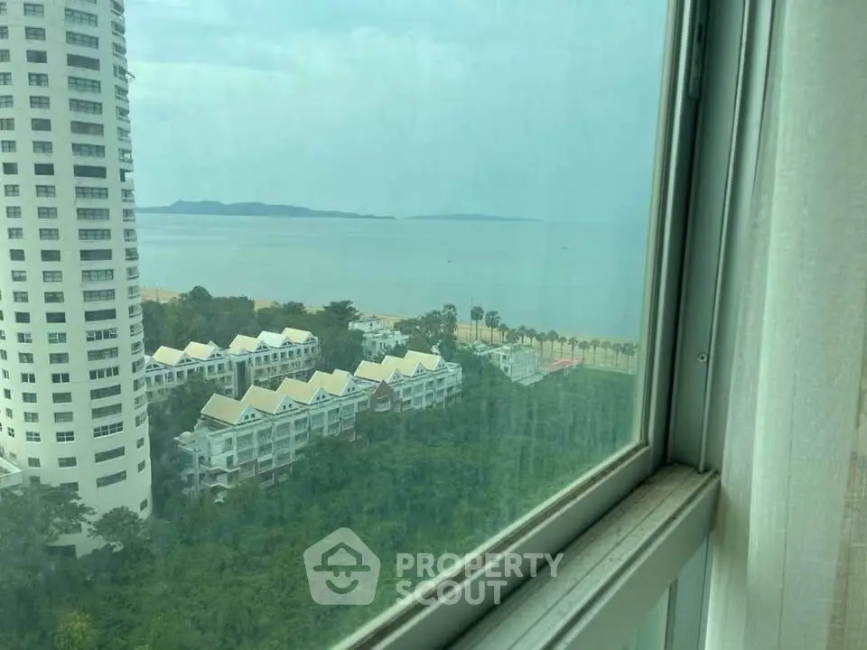 Stunning high-rise view of ocean and cityscape from window, perfect for serene living.