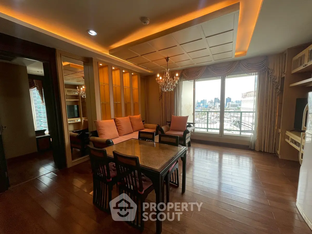 Luxurious living room with elegant chandelier and city view, featuring cozy seating and stylish decor.
