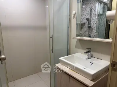 Modern bathroom with sleek sink and glass shower enclosure in contemporary apartment.