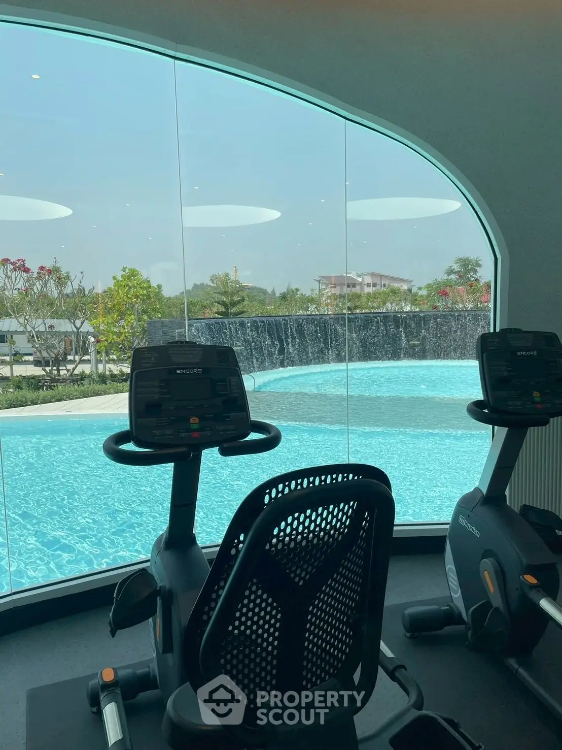 Luxurious gym with pool view and modern exercise equipment in upscale real estate property.