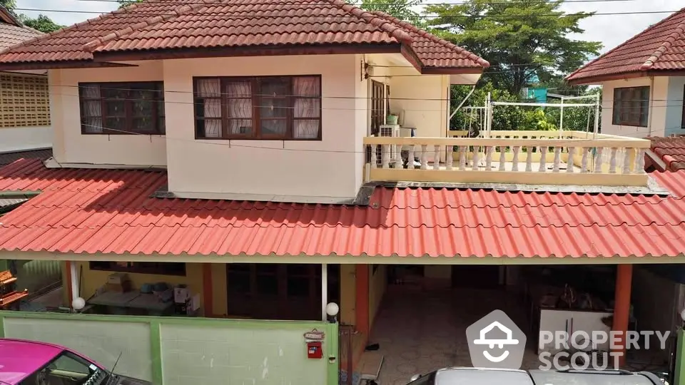 Charming two-story house with red-tiled roof and spacious balcony in a serene neighborhood.