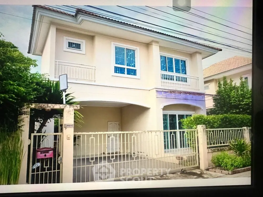 Charming two-story house with gated driveway and lush greenery, perfect for family living.