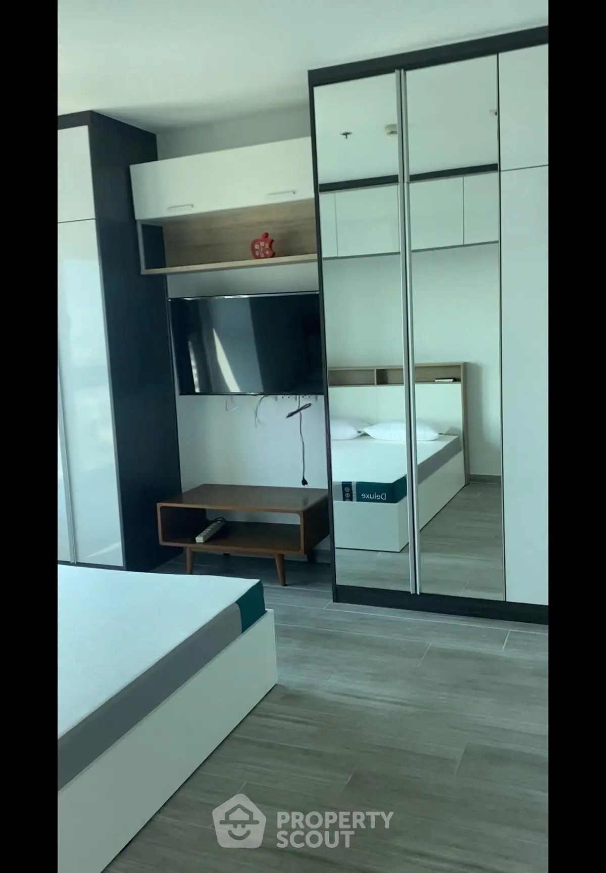 Modern bedroom with sleek mirrored wardrobe and mounted TV