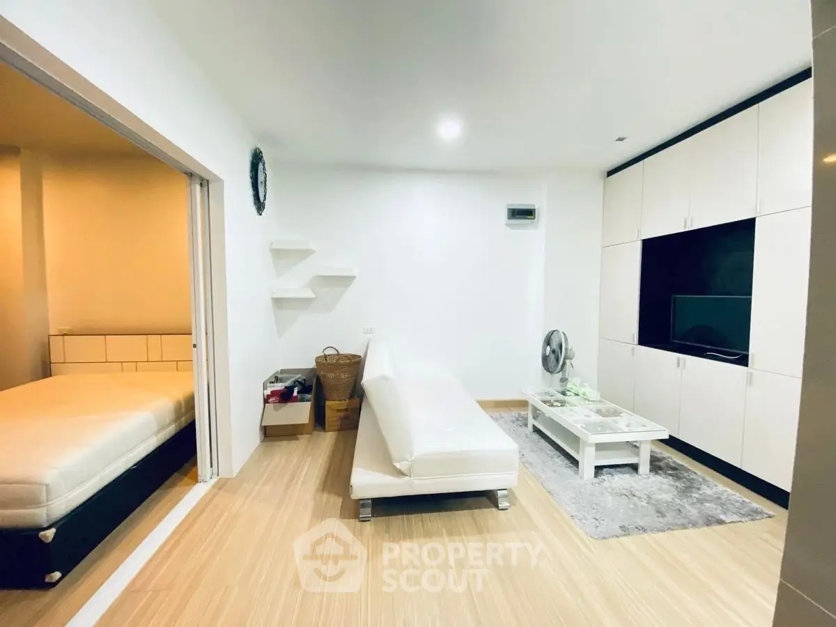 Modern living room with sleek white furniture and cozy bedroom view