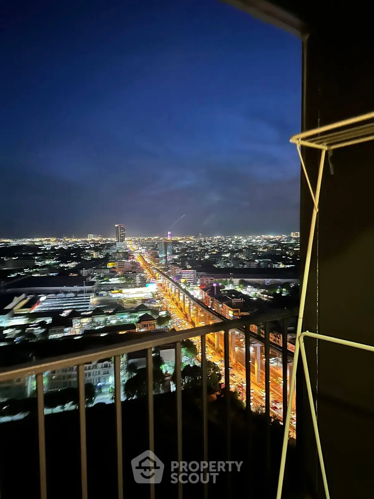 Stunning cityscape view from a high-rise balcony at night, showcasing vibrant city lights and skyline.