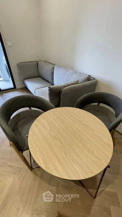 Cozy living room with modern gray sofa and round wooden table, perfect for relaxation.