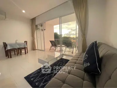 Spacious living room with balcony view, modern furniture, and natural lighting.