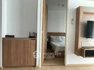 Modern apartment interior with wooden furniture and a glimpse of a cozy bedroom.