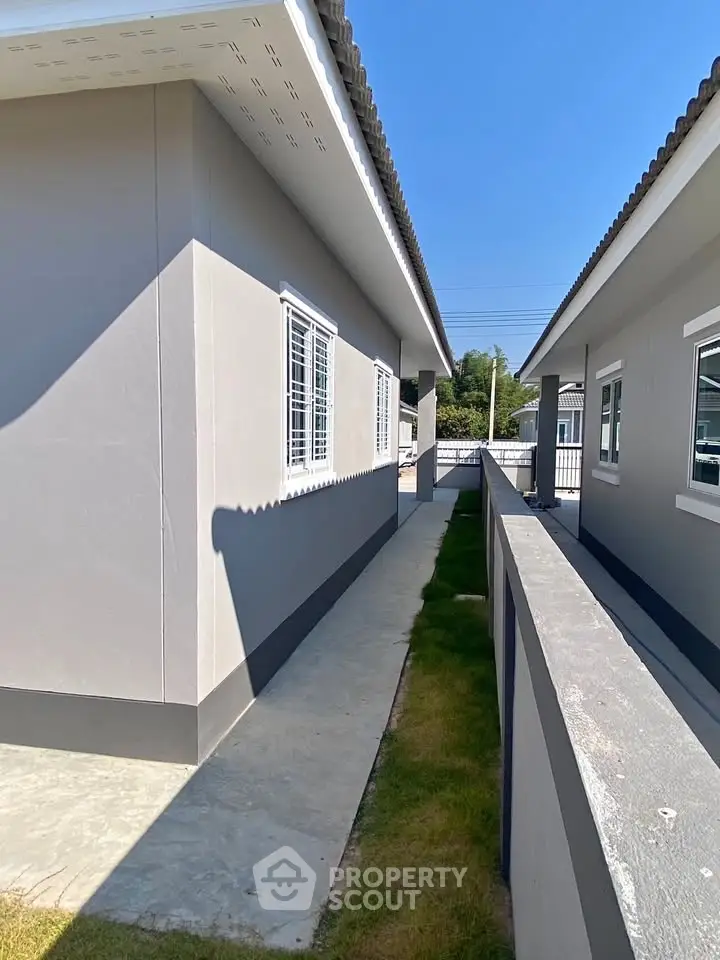 Modern exterior view of a residential building with clean lines and a well-maintained pathway.