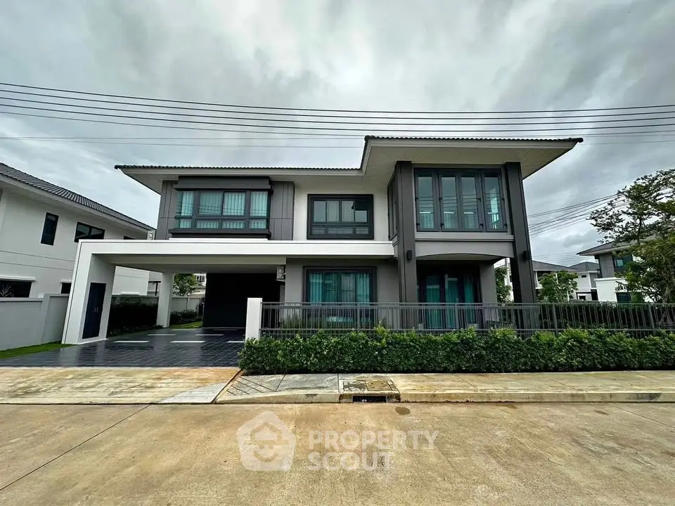 Modern two-story house with sleek design and spacious driveway in a suburban neighborhood.