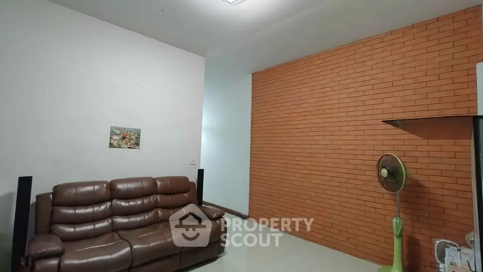 Cozy living room with brown leather sofa and brick accent wall, perfect for relaxation.