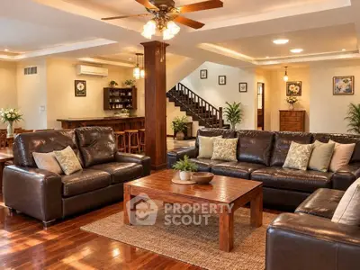 Spacious living room with elegant leather sofas and wooden coffee table, featuring warm lighting and open layout.