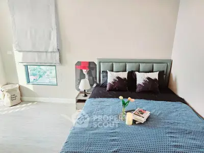 Modern bedroom with stylish decor and large window offering natural light.