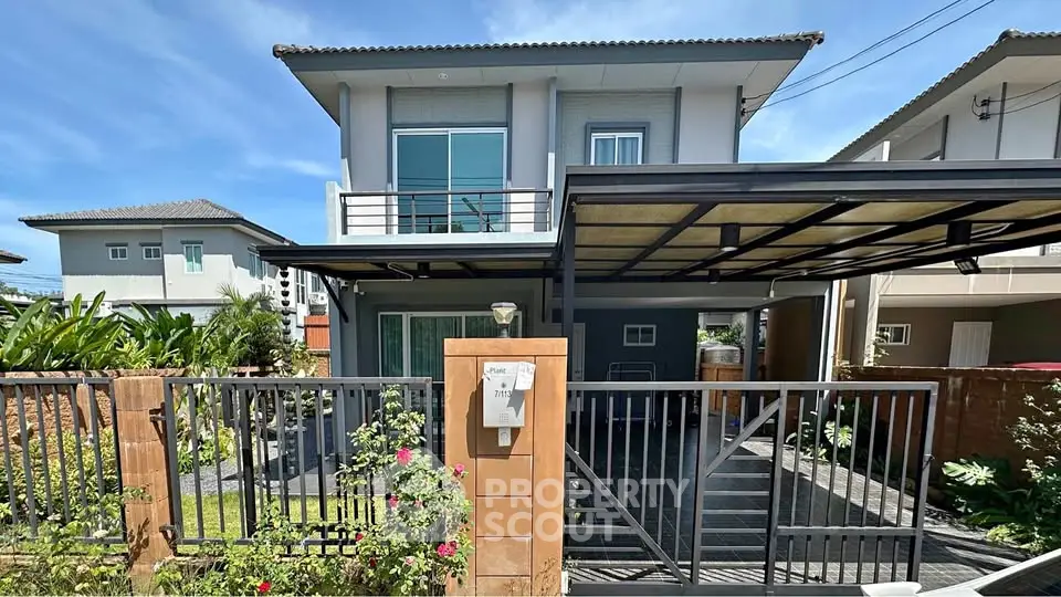 Modern two-story house with gated entrance and carport in a suburban neighborhood.
