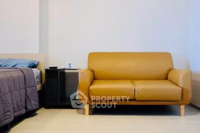 Cozy studio apartment with modern leather sofa and stylish bed setup.