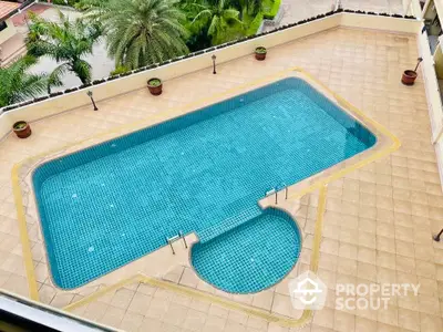 Luxurious outdoor swimming pool with elegant tile design and lush greenery view.