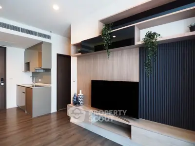 Modern living room with stylish TV unit and open kitchen layout in a contemporary apartment.